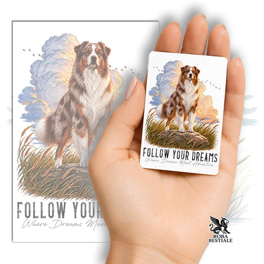 Calamita rettangolare con Australian Shepherd red merle seduto, scritta “Follow Your Dreams”.